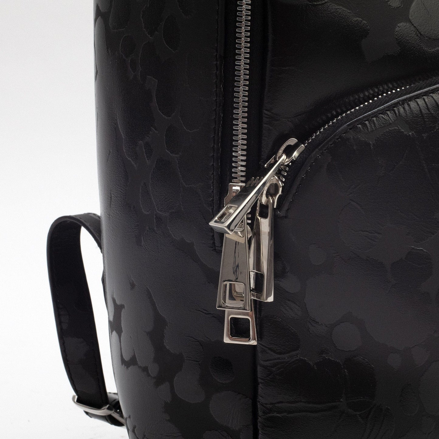 video of a black Italian leather back pack with spotted print and silver zippers.