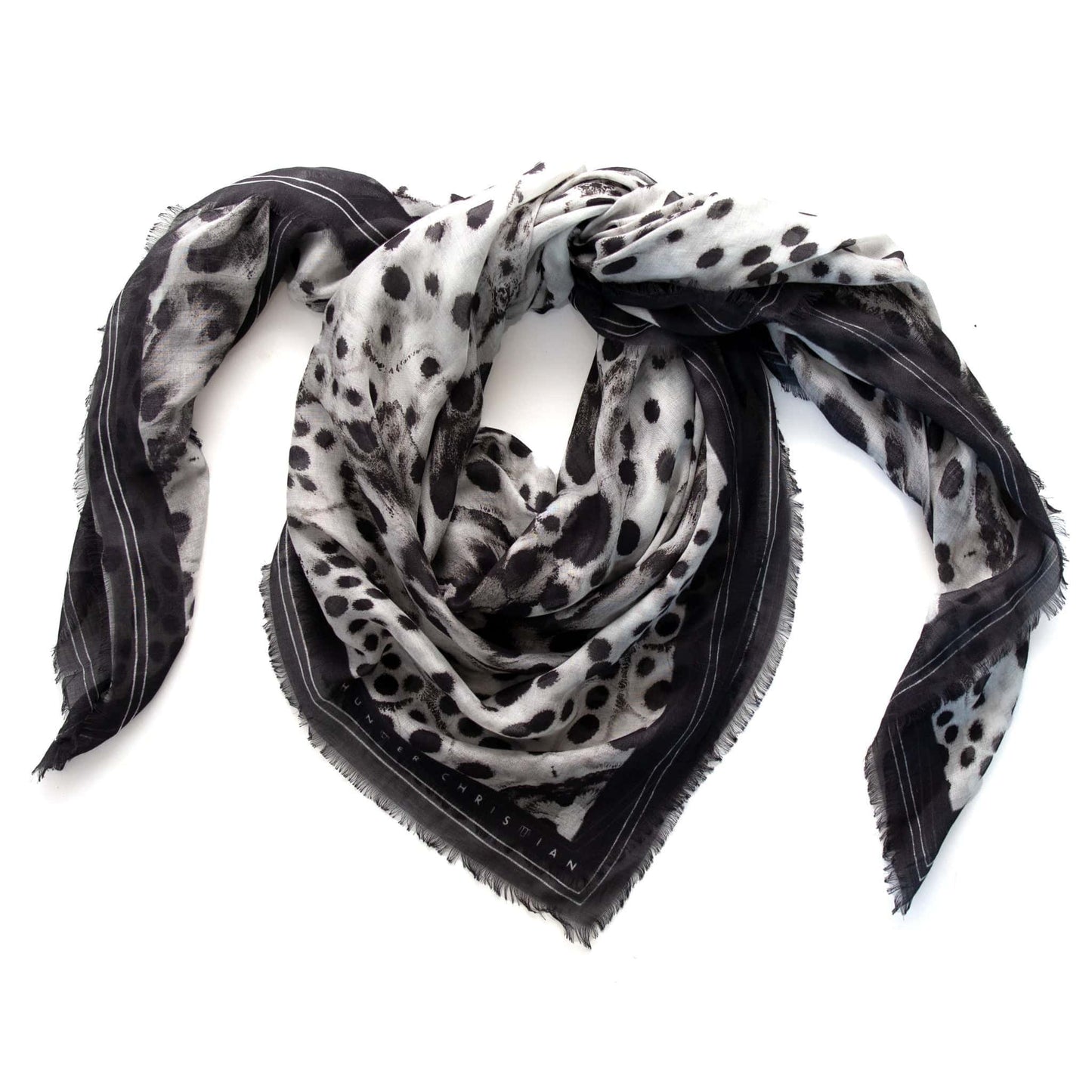 Coiled flat lay of the Hemera scarf by Hunter Christian, revealing its airy modal-silk texture and black-and-white inkblot design with fluid movement and depth.