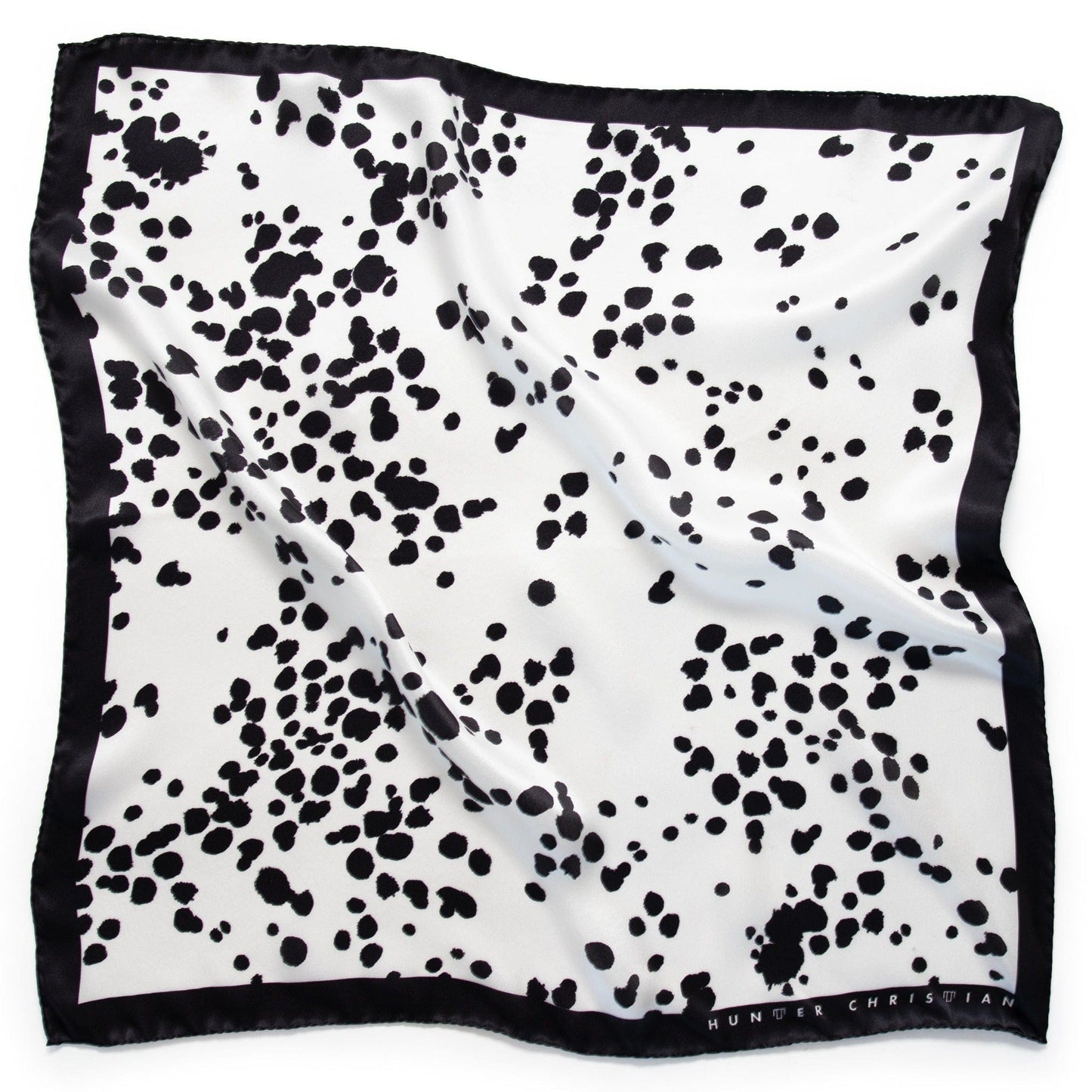 Flat lay of Ko Bandana – First Edition with abstract black print on white silk square and solid black border